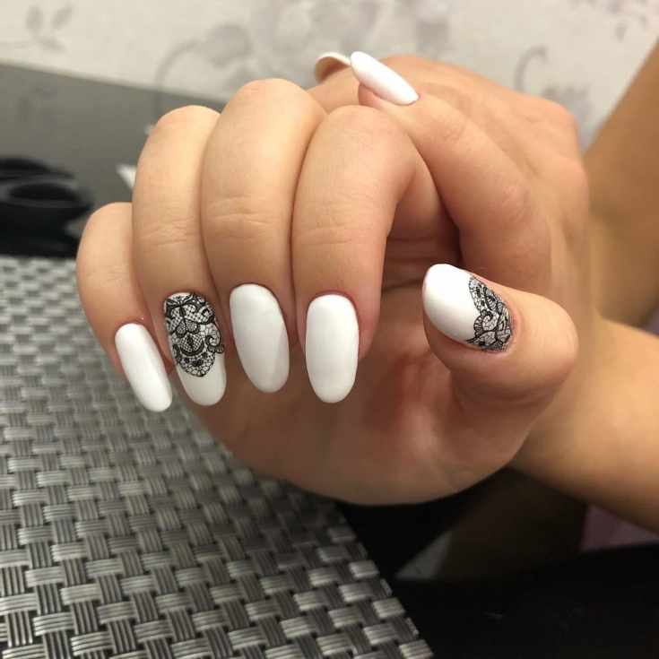 Белый матовый маникюр на длинные овальные ногти с черным кружевом на двух ногтях